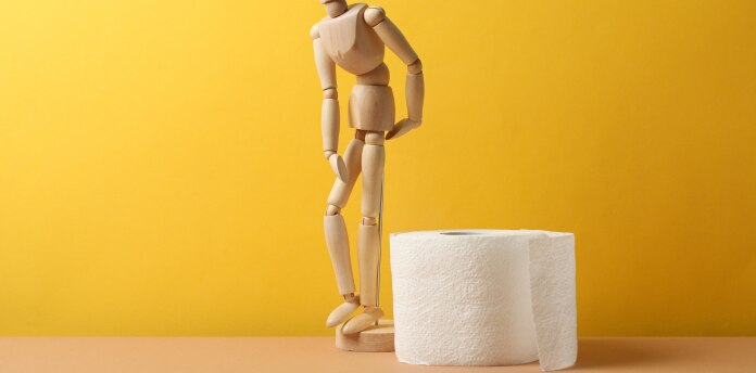 Boneco articulado de madeira junto a um rolo de papel higiênico